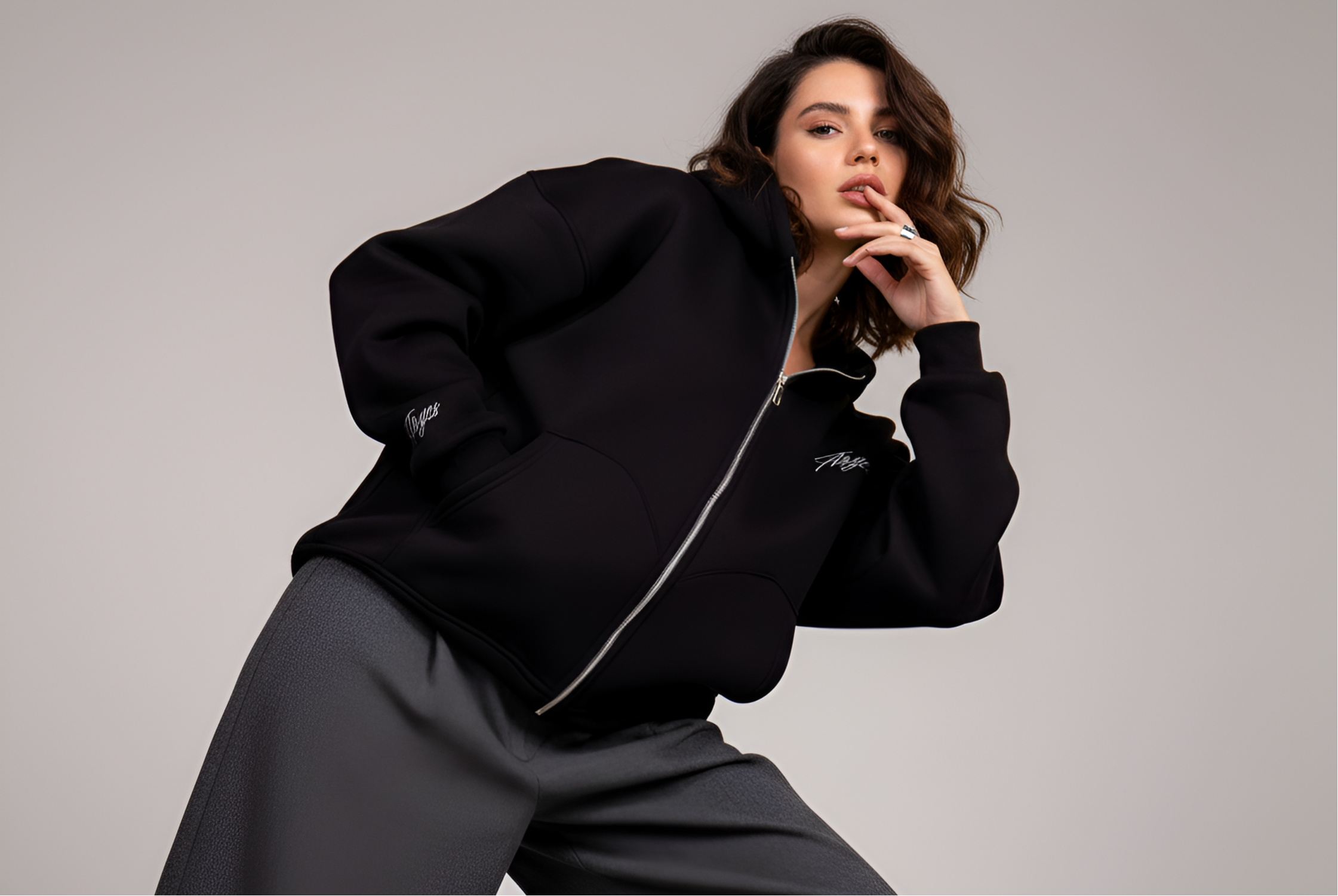 Woman wearing a black hoodie with Aryes logo on a gray background